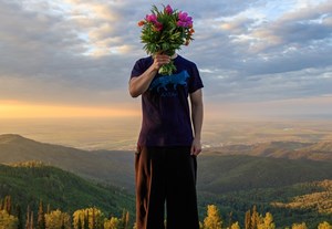 Man_Holding_A_Bouquet_of_Flowers_On_Top_Of_A_Mountain